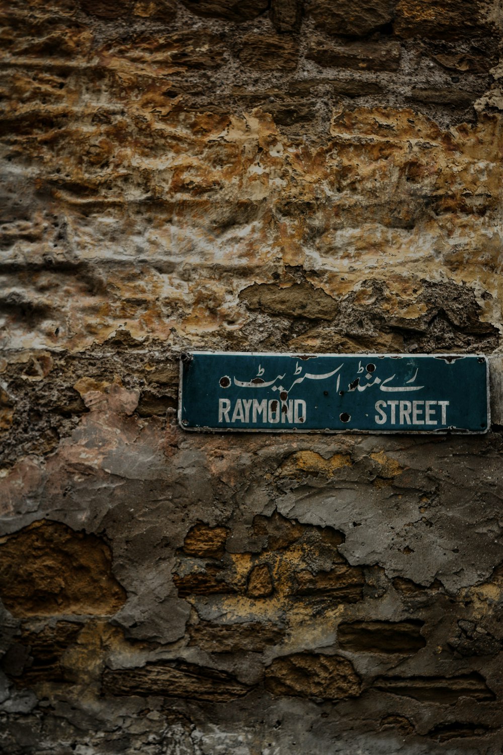 a blue street sign mounted to the side of a stone wall