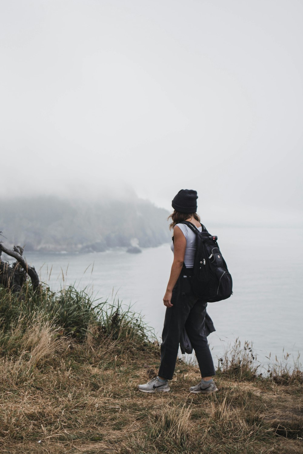 man in black backpack standing on green grass field near body of water during daytime