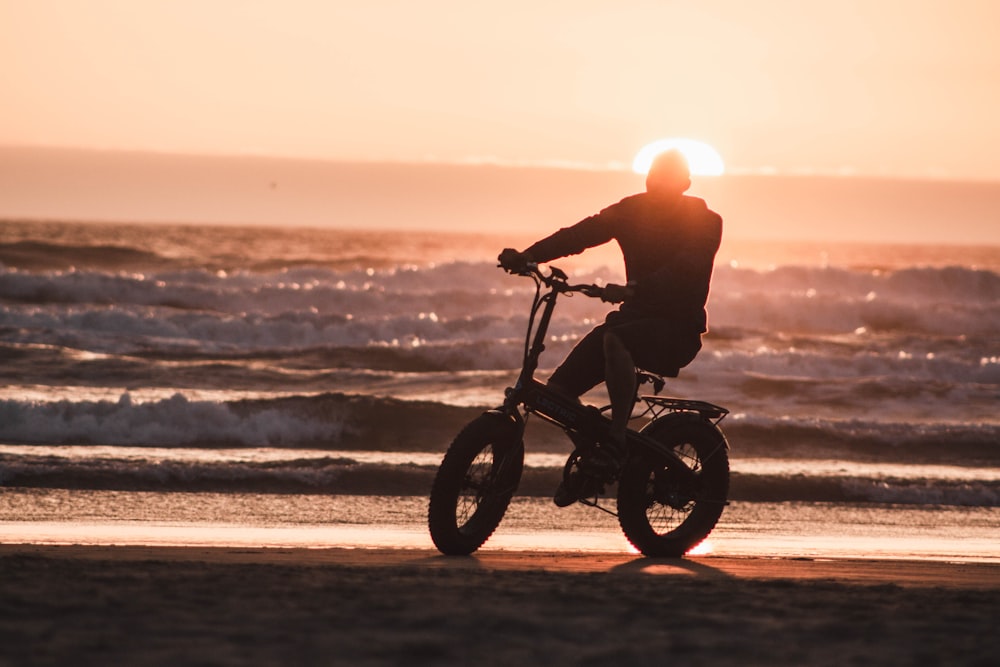 man in black jacket riding on black motorcycle on beach during sunset