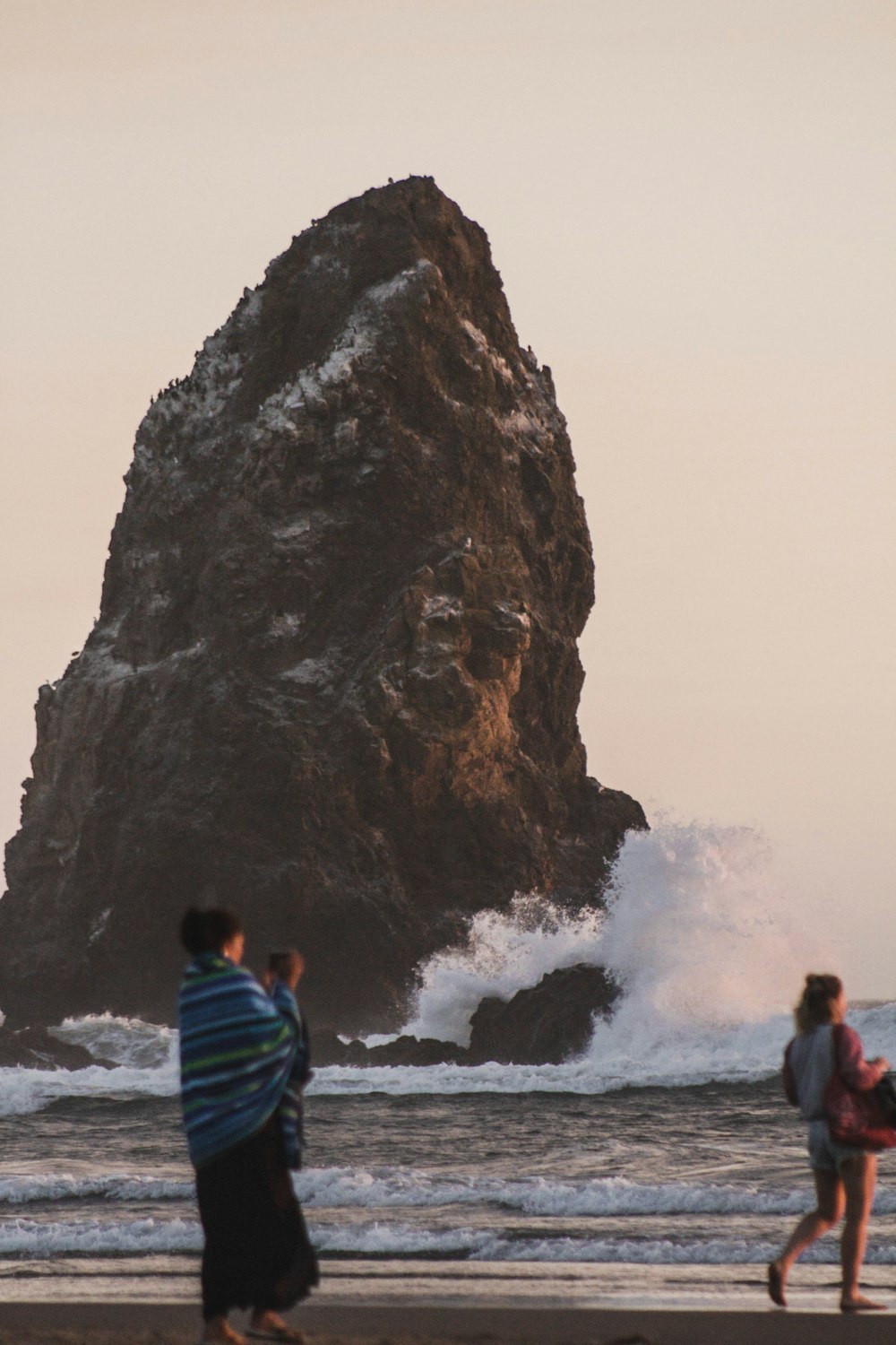 man in blue and yellow striped shirt standing on seashore near brown rock formation during daytime