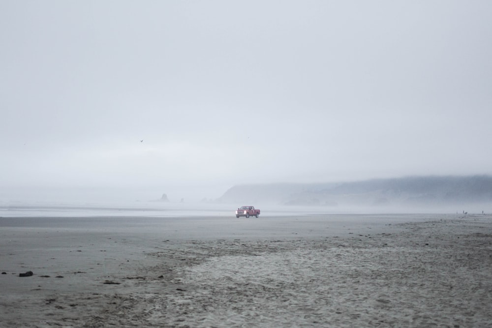 person in red shirt standing on gray sand during daytime