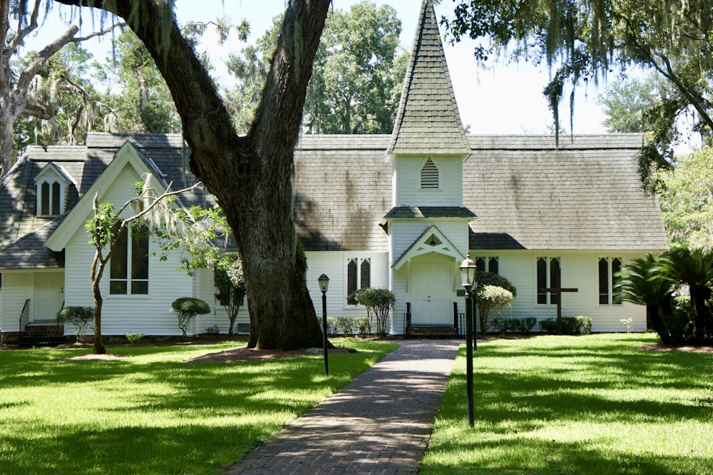 white and brown concrete house near green grass field and trees during daytime