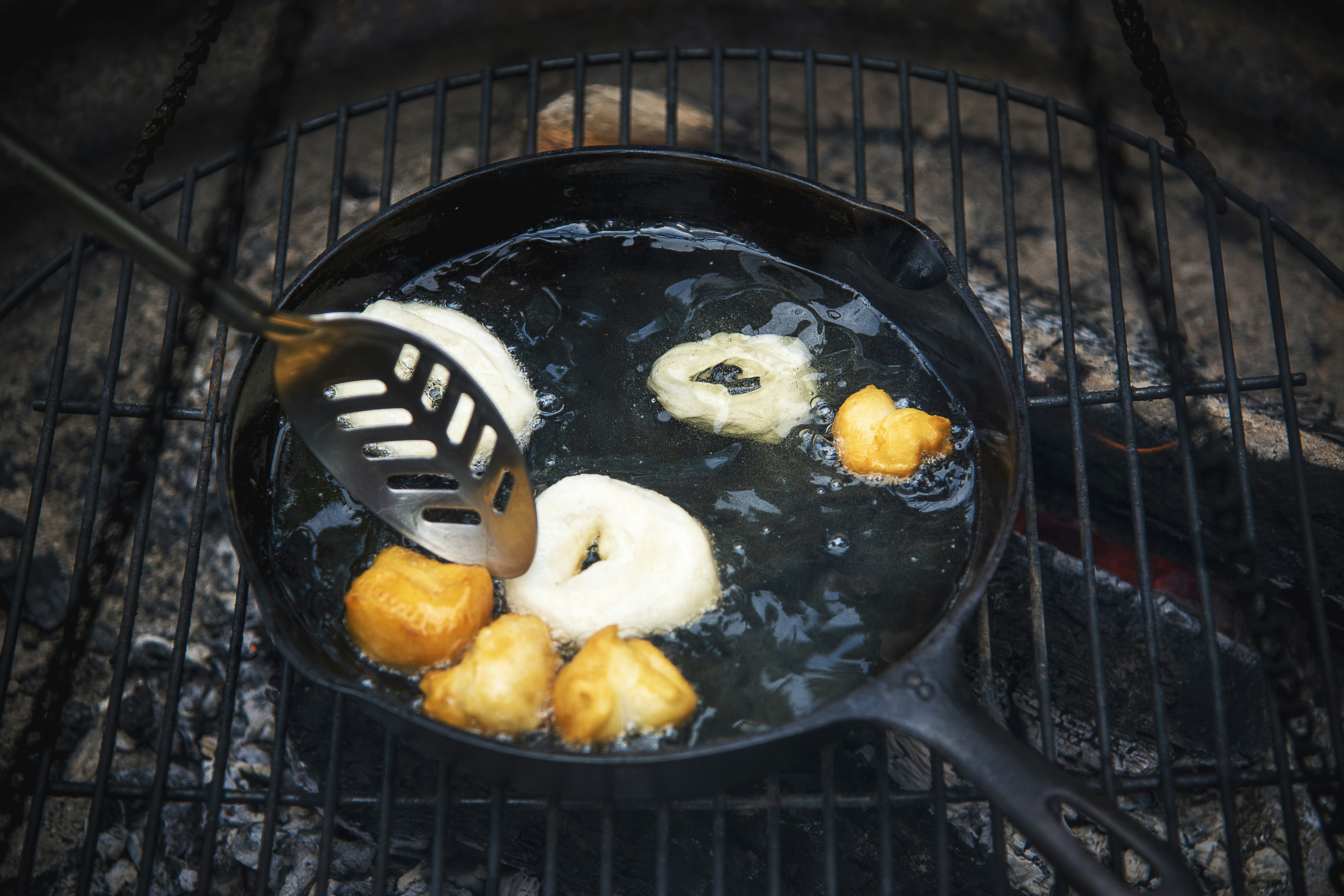 black frying pan on brown wooden table; tortilla pan; tortilla in skillet