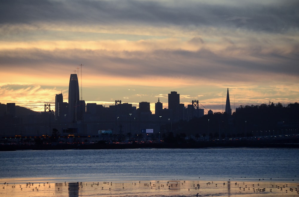 city skyline across body of water during sunset