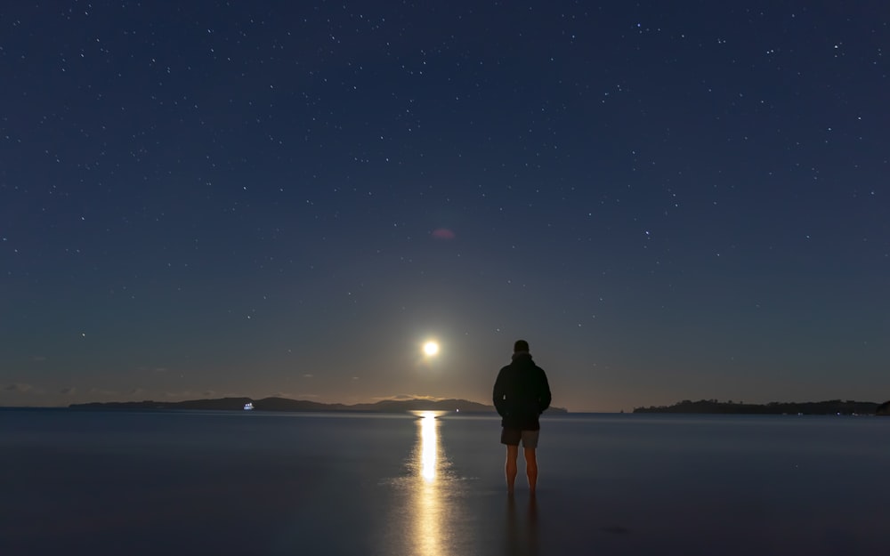 man standing on seashore during night time