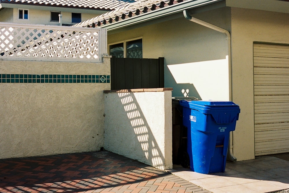 blue trash bins beside white wall