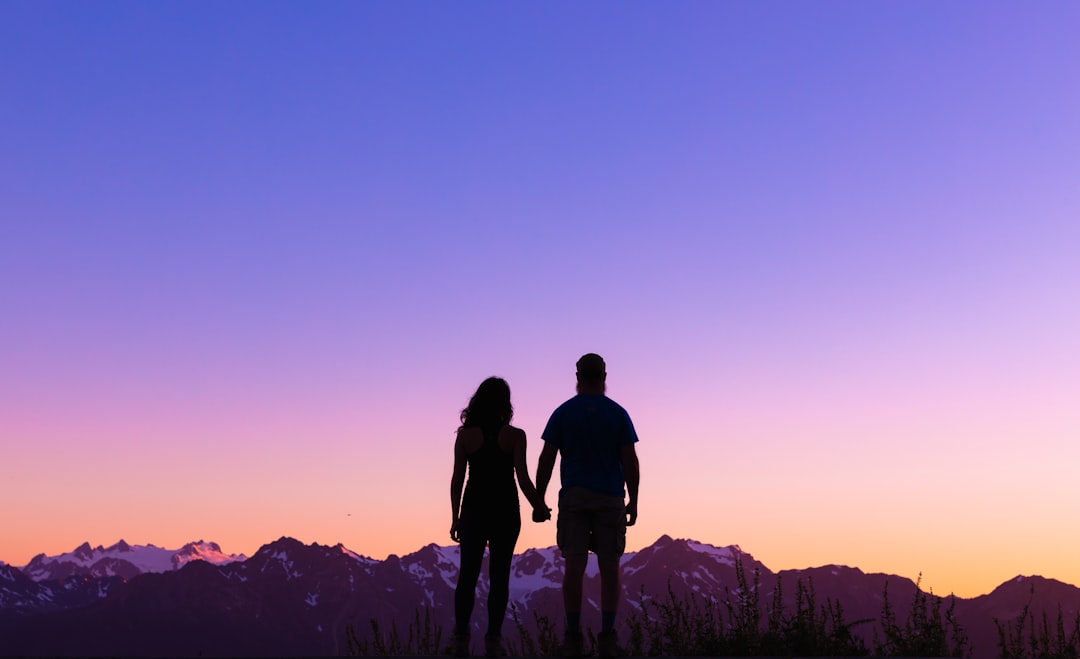 silhouette of 2 men standing on mountain during sunset