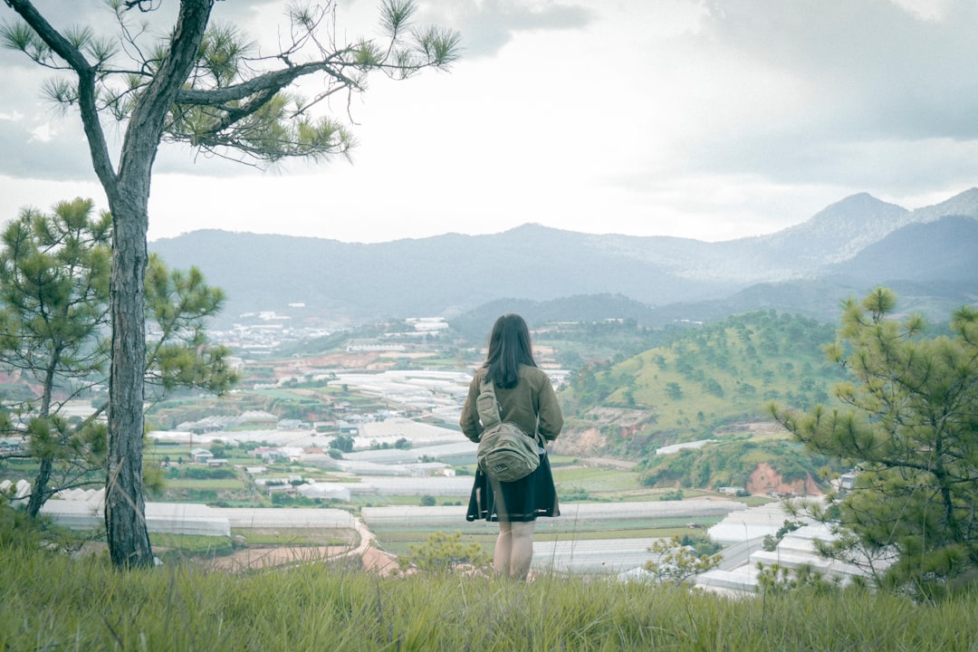 woman in black jacket standing on green grass field near body of water during daytime