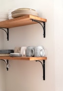Wooden shelves with industrial metal supports arranged neatly against a white wall.