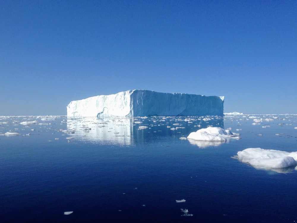 昼間の青空の下、青い海に浮かぶ白と灰色の岩層