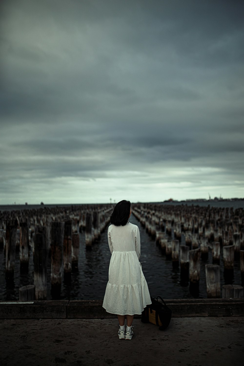 woman in white dress walking on brown wooden dock during daytime