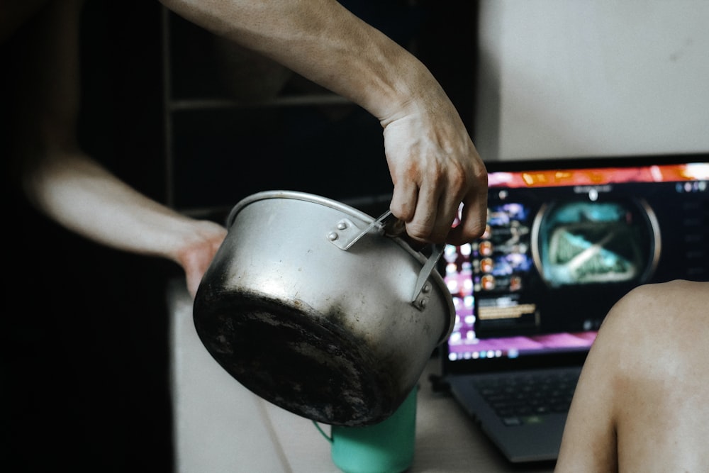 person holding stainless steel teapot