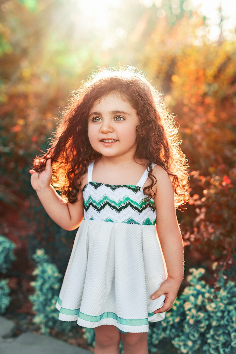 girl in white and teal sleeveless dress standing on green grass field during daytime