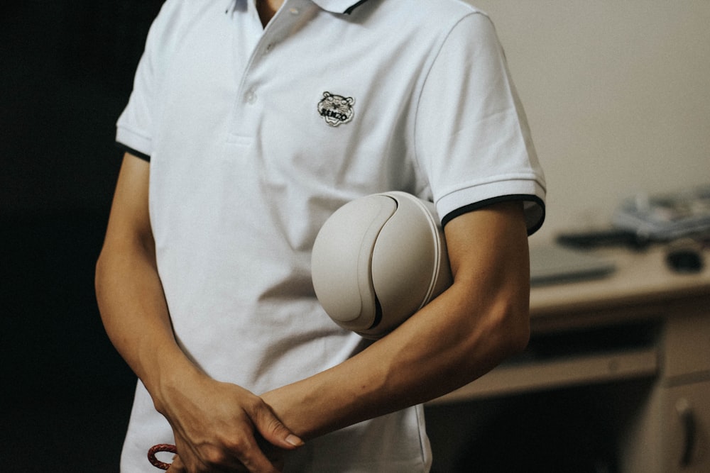man in white polo shirt holding white nike soccer ball