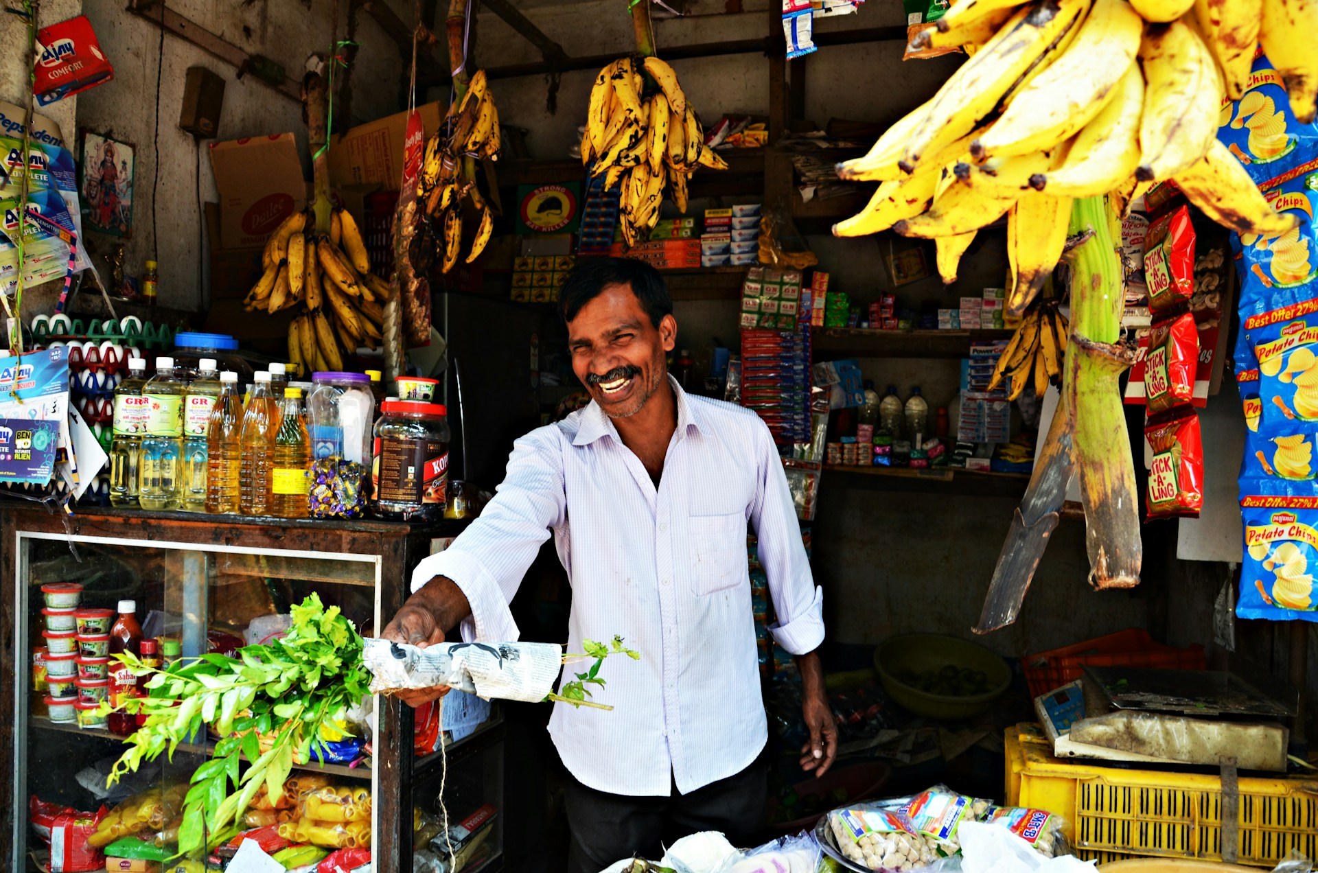 man in white button up shirt and black pants standing in front of fruit stand