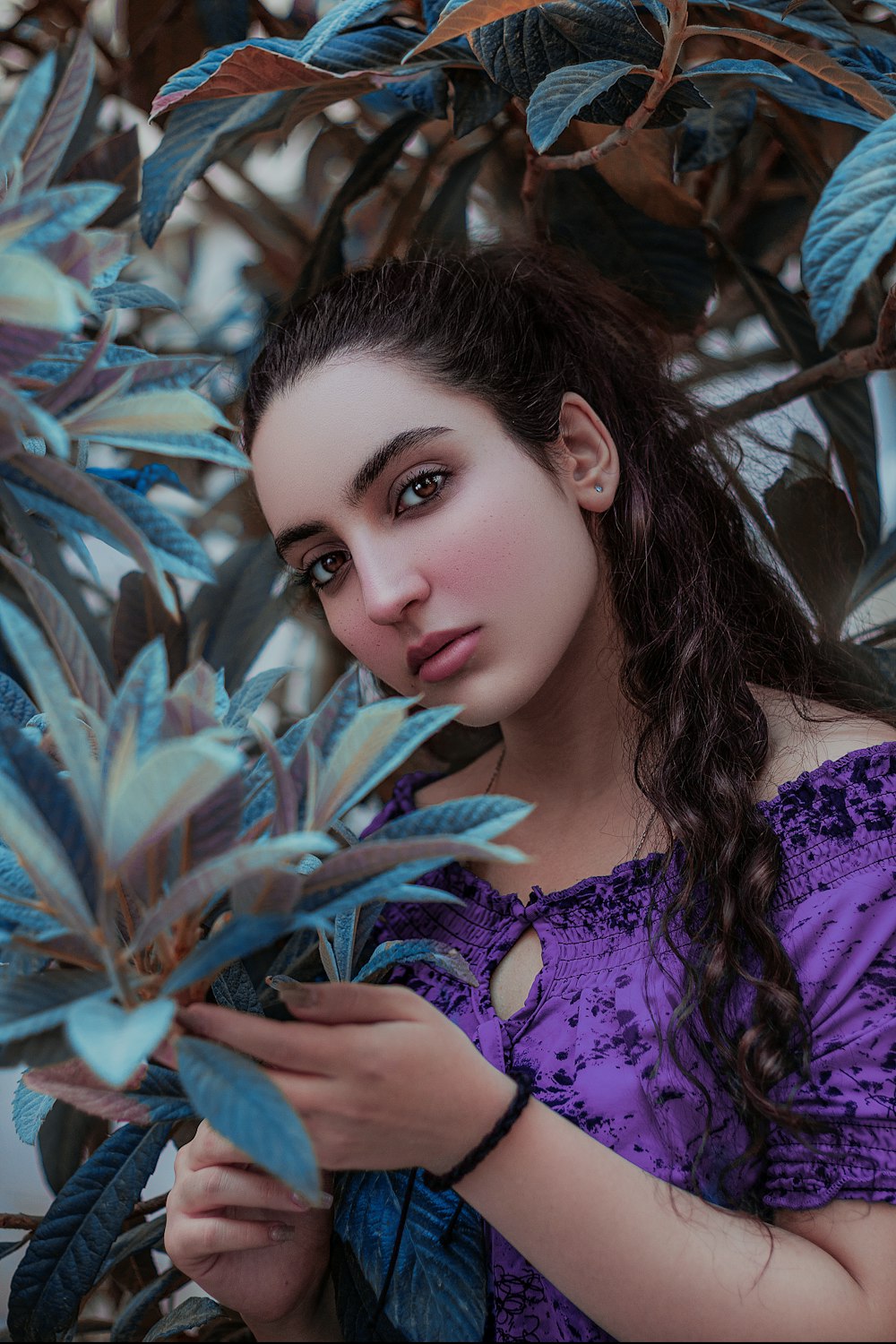 a woman in a purple dress is holding a plant