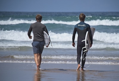 A happy family carrying inflatable surfboards toward the ocean on a sunny day.