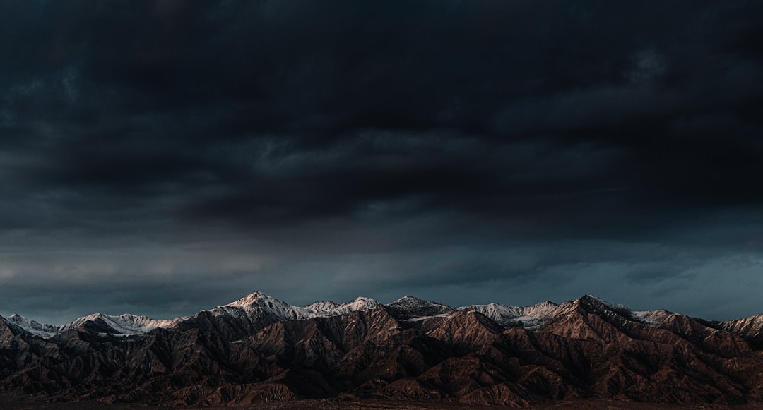 brown and white mountains under gray clouds