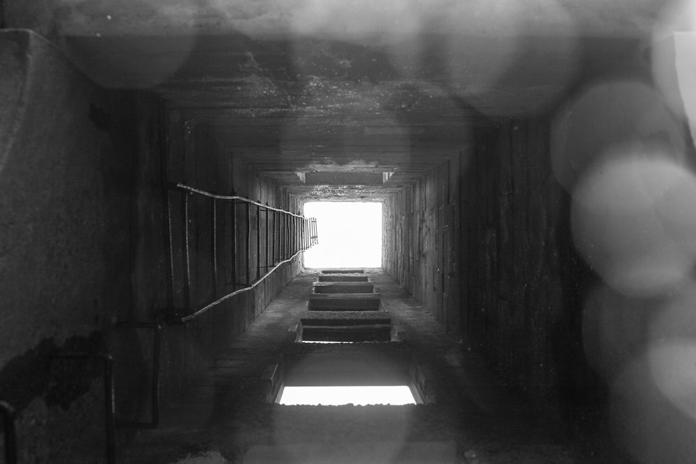 grayscale photo of tunnel with light