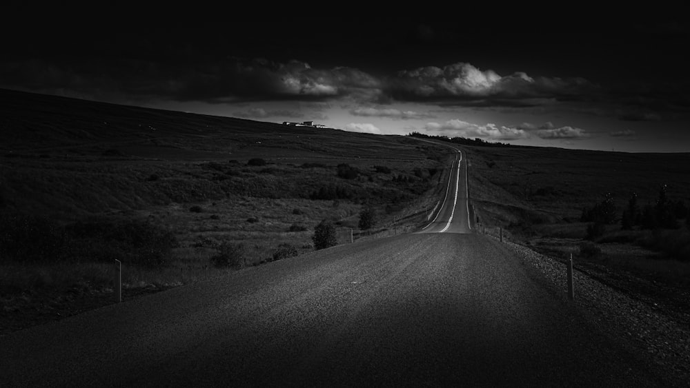 grayscale photo of road in the middle of snow covered field