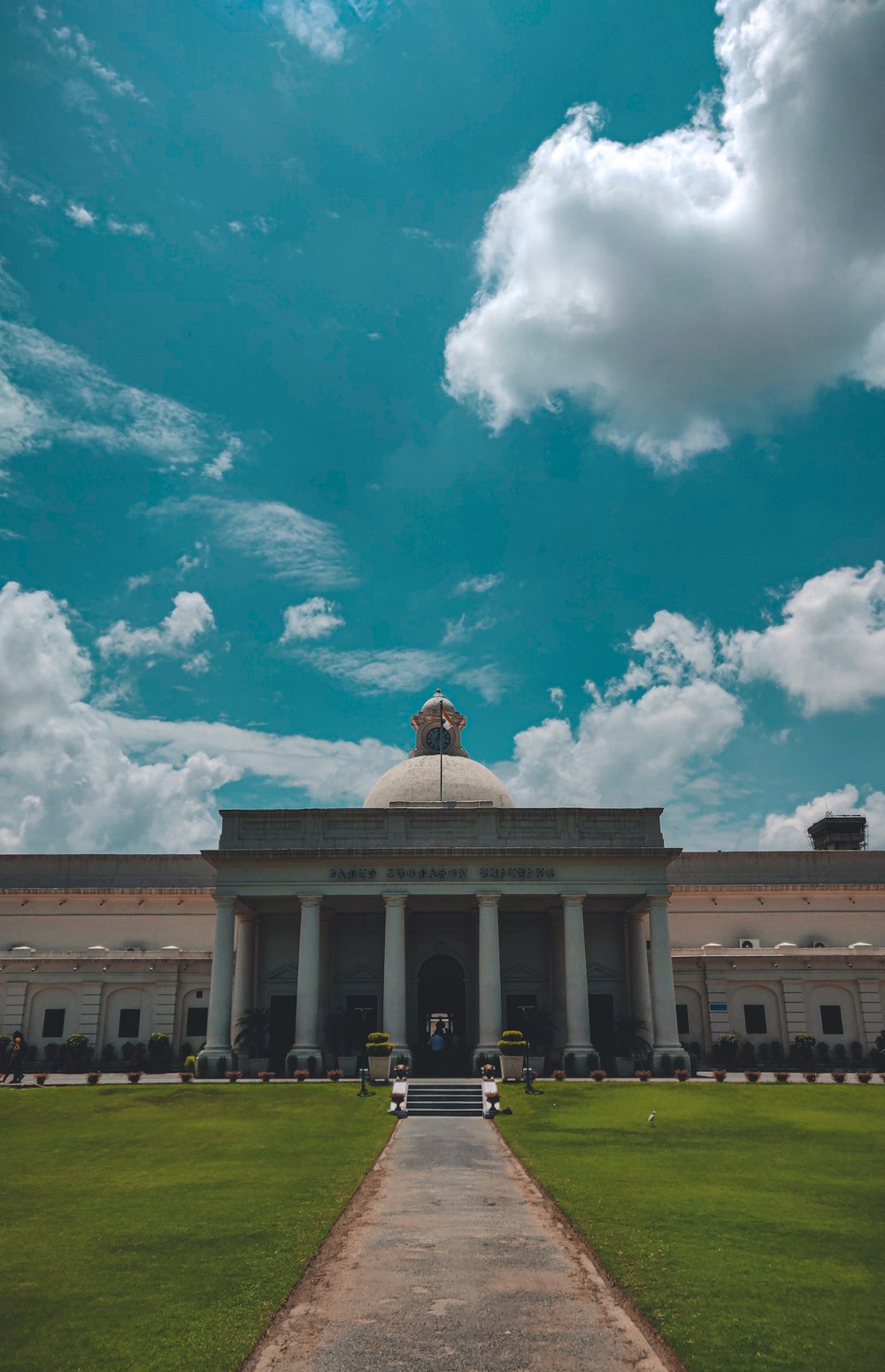 white concrete building under blue sky and white clouds during daytime