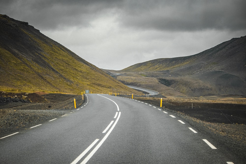 gray concrete road near mountain during daytime