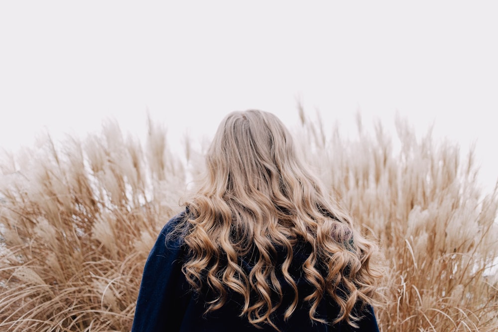 woman in blue long sleeve shirt standing on brown grass field during daytime