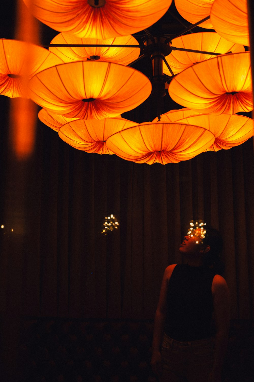 woman in black dress standing near red string lights