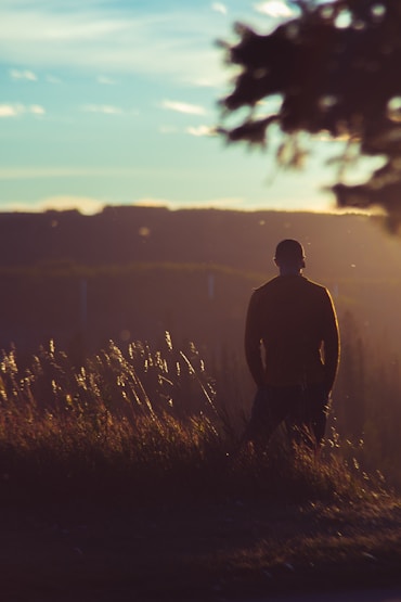man in black jacket standing on grass field during daytime