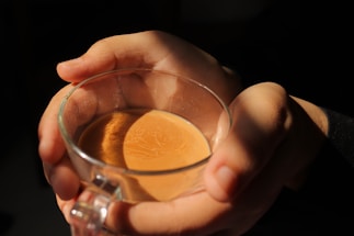 A gentle hand holding a warm cup of tea by a cozy window.