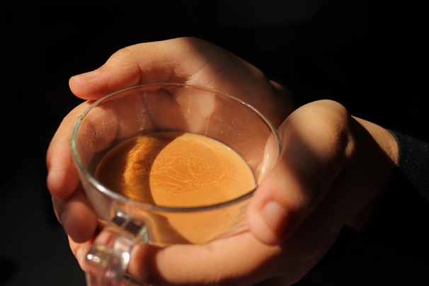 A close-up of hands holding a steaming cup of tea.