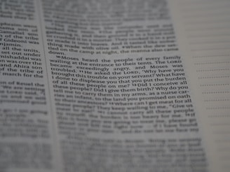 The image contains a close-up view of a page from a printed book. The text is clear and legible, with paragraphs justified and a heading that indicates a verse or section. The focus is on a particular passage, highlighting the dialogue attributed to Moses.