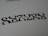 Black symmetrical shapes are printed on a white background, resembling a stylized word or pattern with artistic font design.