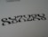 Black symmetrical shapes are printed on a white background, resembling a stylized word or pattern with artistic font design.