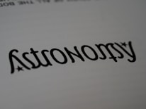 A close-up of the word 'Astronomy' written in a stylized font, resembling calligraphy. The text is black on a white background, with small star-like accents near the letters.