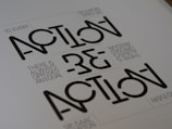 Text appears in a stylized geometric font with the words 'ACTION' and 'REACTION' prominently visible. The phrase 'TO EVERY ACTION THERE IS ALWAYS OPPOSED AN EQUAL REACTION' is included in a smaller, simpler font. The layout is minimalist with a monochromatic color scheme.