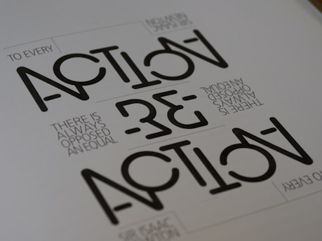Text appears in a stylized geometric font with the words 'ACTION' and 'REACTION' prominently visible. The phrase 'TO EVERY ACTION THERE IS ALWAYS OPPOSED AN EQUAL REACTION' is included in a smaller, simpler font. The layout is minimalist with a monochromatic color scheme.