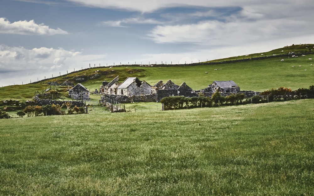 Casa blanca y gris en campo de hierba verde bajo nubes blancas y cielo azul durante el día