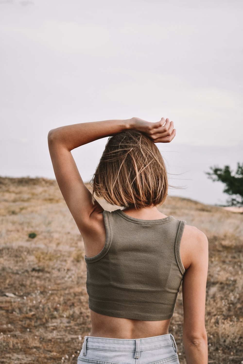 woman in gray tank top standing on brown field during daytime