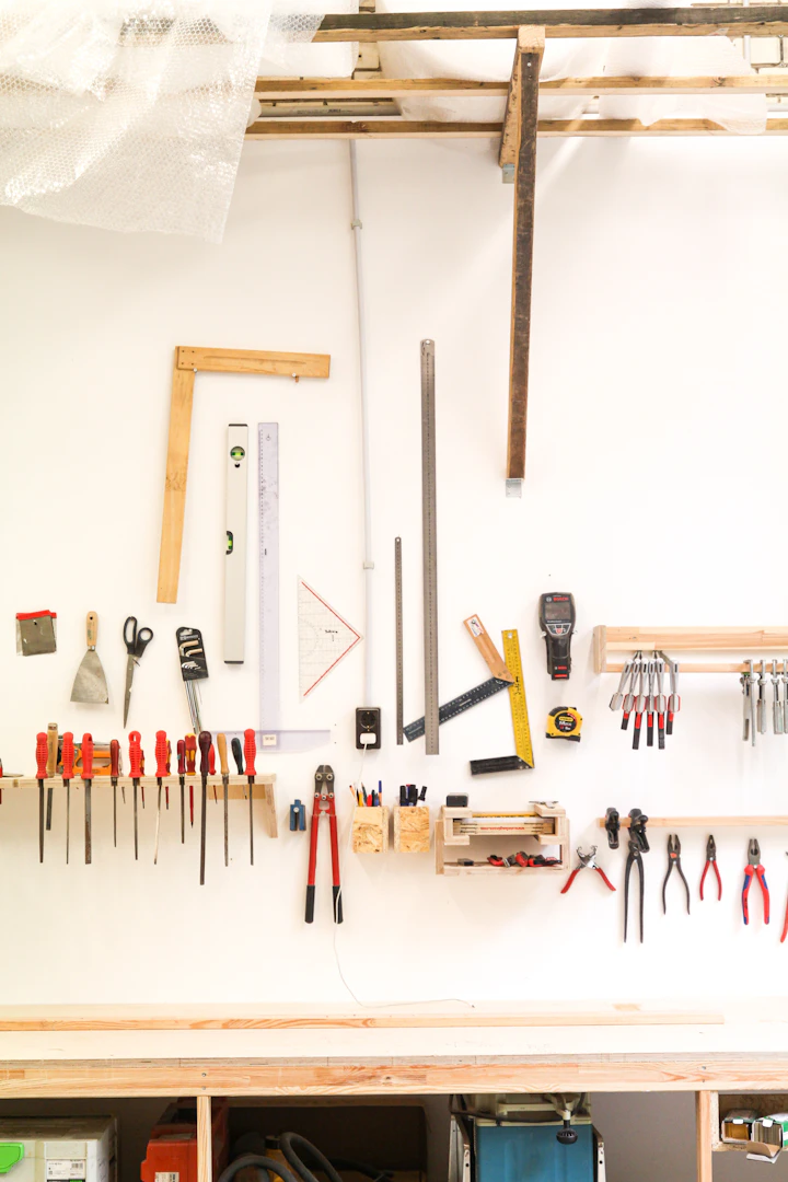 A workshop wall with levels, rulers, screwdrivers and pliers hung in neat rows