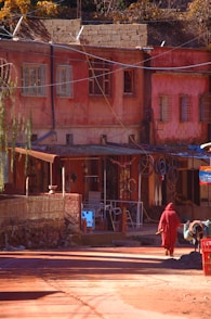 man in red jacket walking on sidewalk during daytime