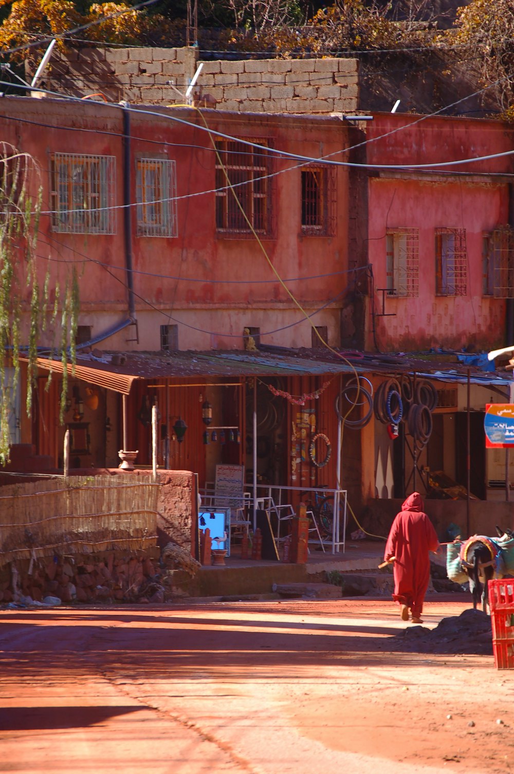 man in red jacket walking on sidewalk during daytime