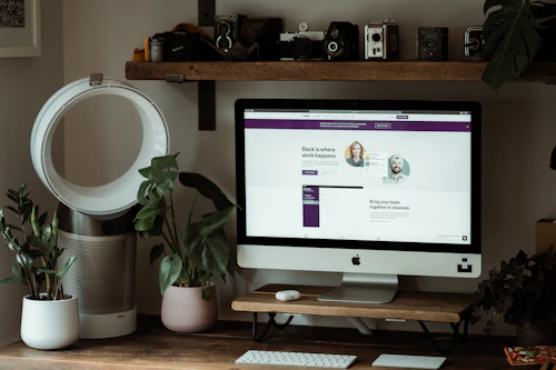 Silver iMac on a brown wooden table in a workspace