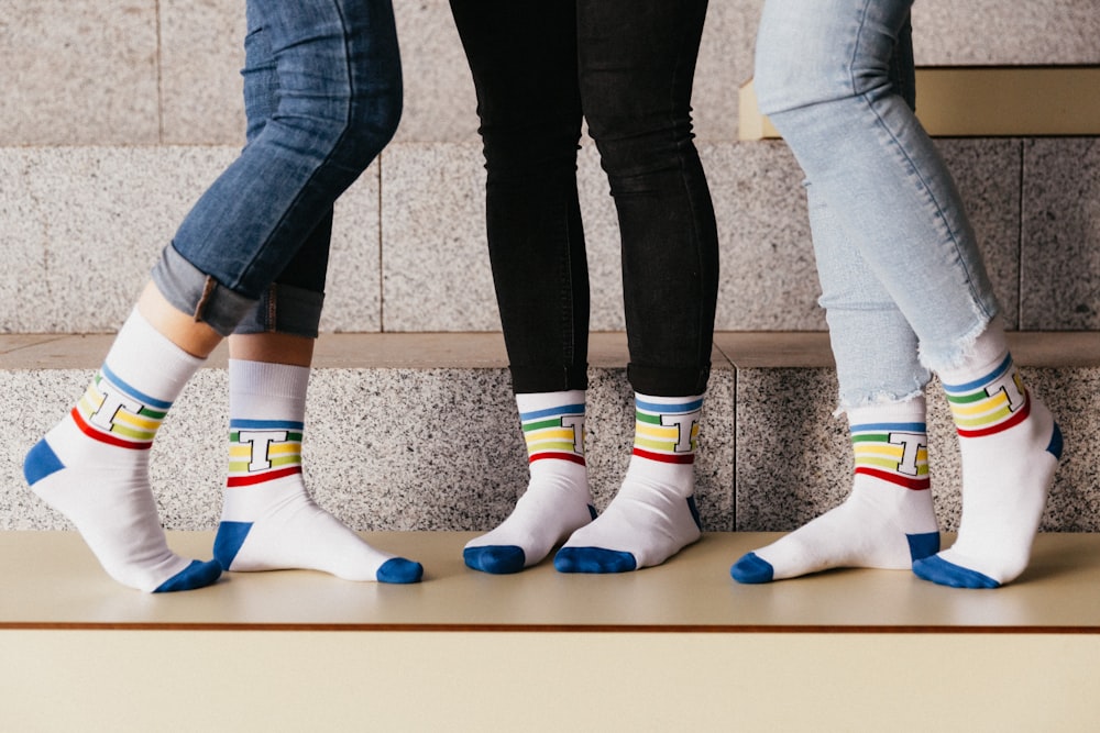 Persona con jeans de mezclilla azul y calcetines blancos, azules y amarillos