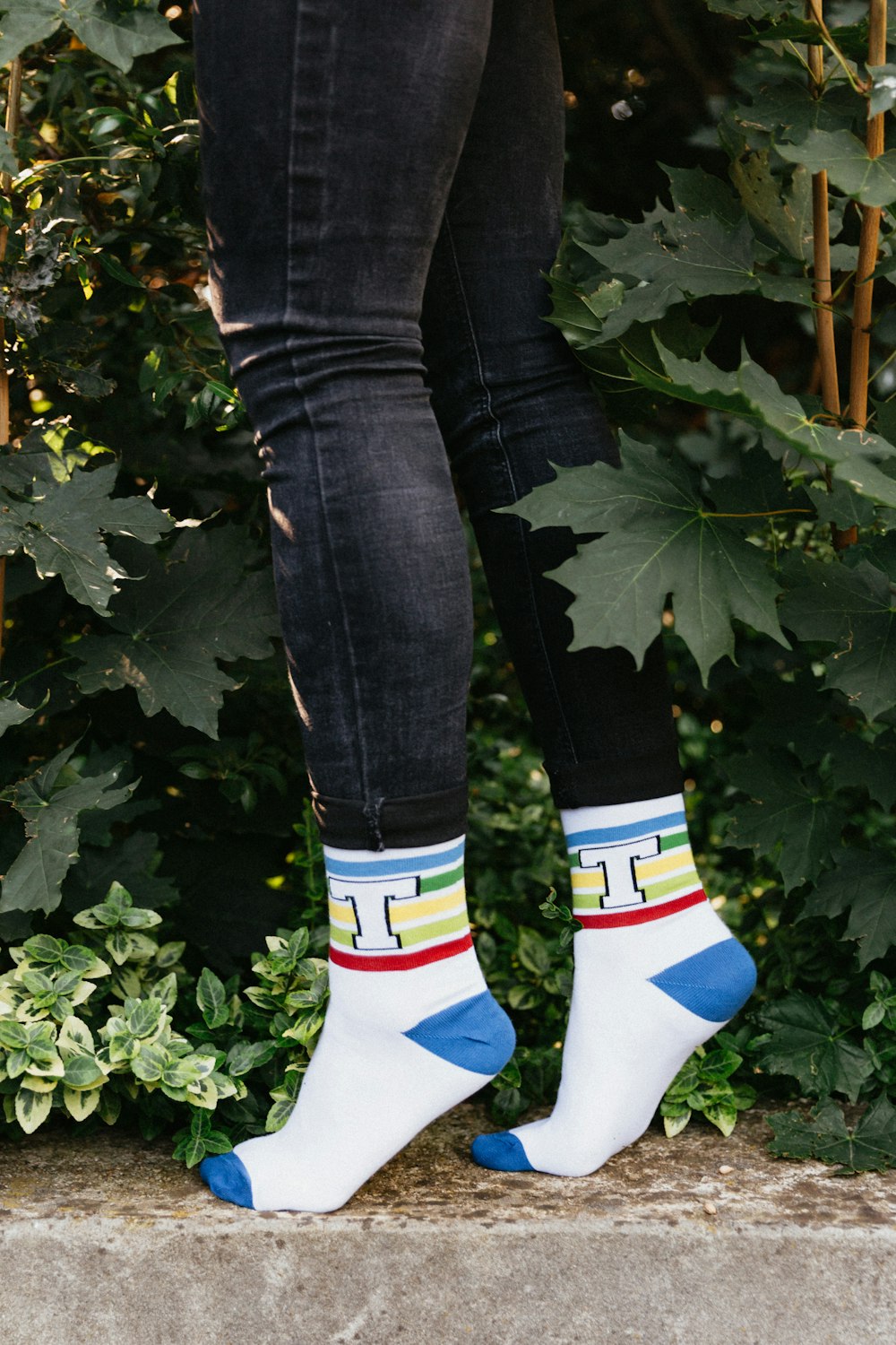 person in blue denim jeans and white socks standing on green grass