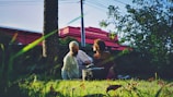 Two caregivers assisting an elderly person in a sunny park.