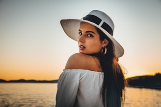 Model wearing a crisp white polo shirt standing by the seaside at sunset