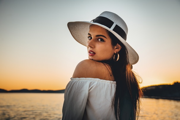 Model wearing a crisp white polo shirt standing by the seaside at sunset