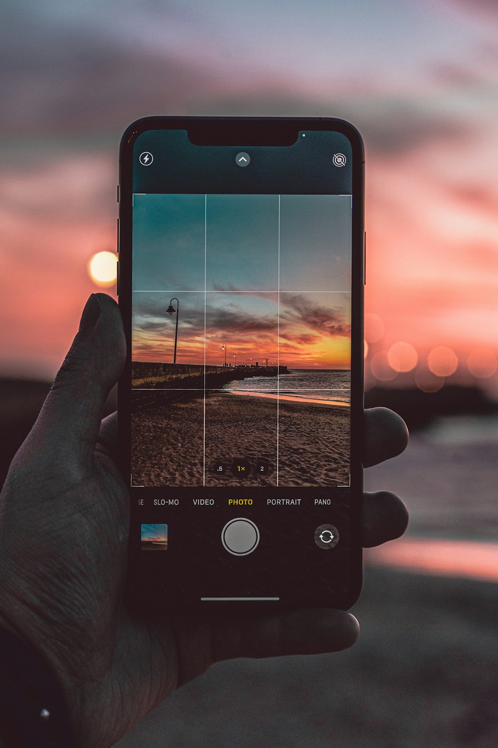 person holding iphone taking photo of sunset