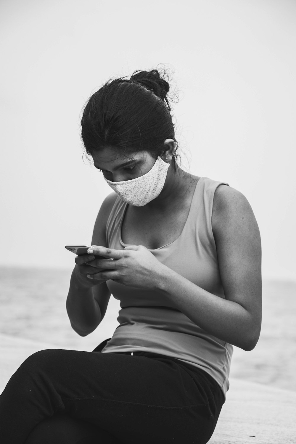 woman in tank top holding smartphone